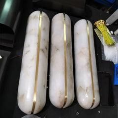 Three white cylindrical objects with gold bands on a black surface