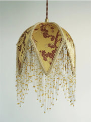 Decorative lamp with floral design and beaded fringe on a plain background