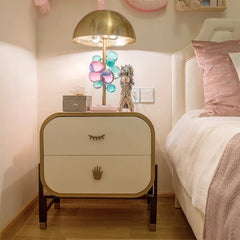 Table lamp with a gold dome shade and crystal globes on a bedside table in a bedroom setting.