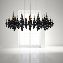 Black globe cluster pendant light against a white wall with a window in the background, showing a reflective surface below.