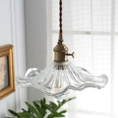 Vintage-style pendant light with clear glass shade and brass fixture in a room setting.