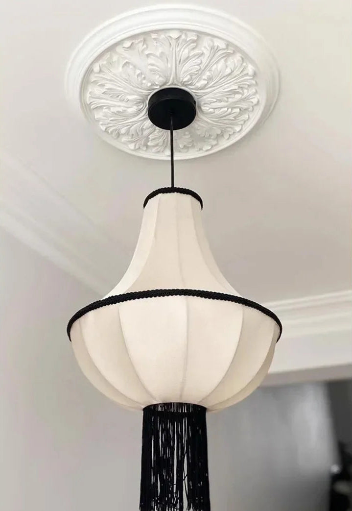 Ceiling light fixture with decorative white shade and black trim on a ceiling.