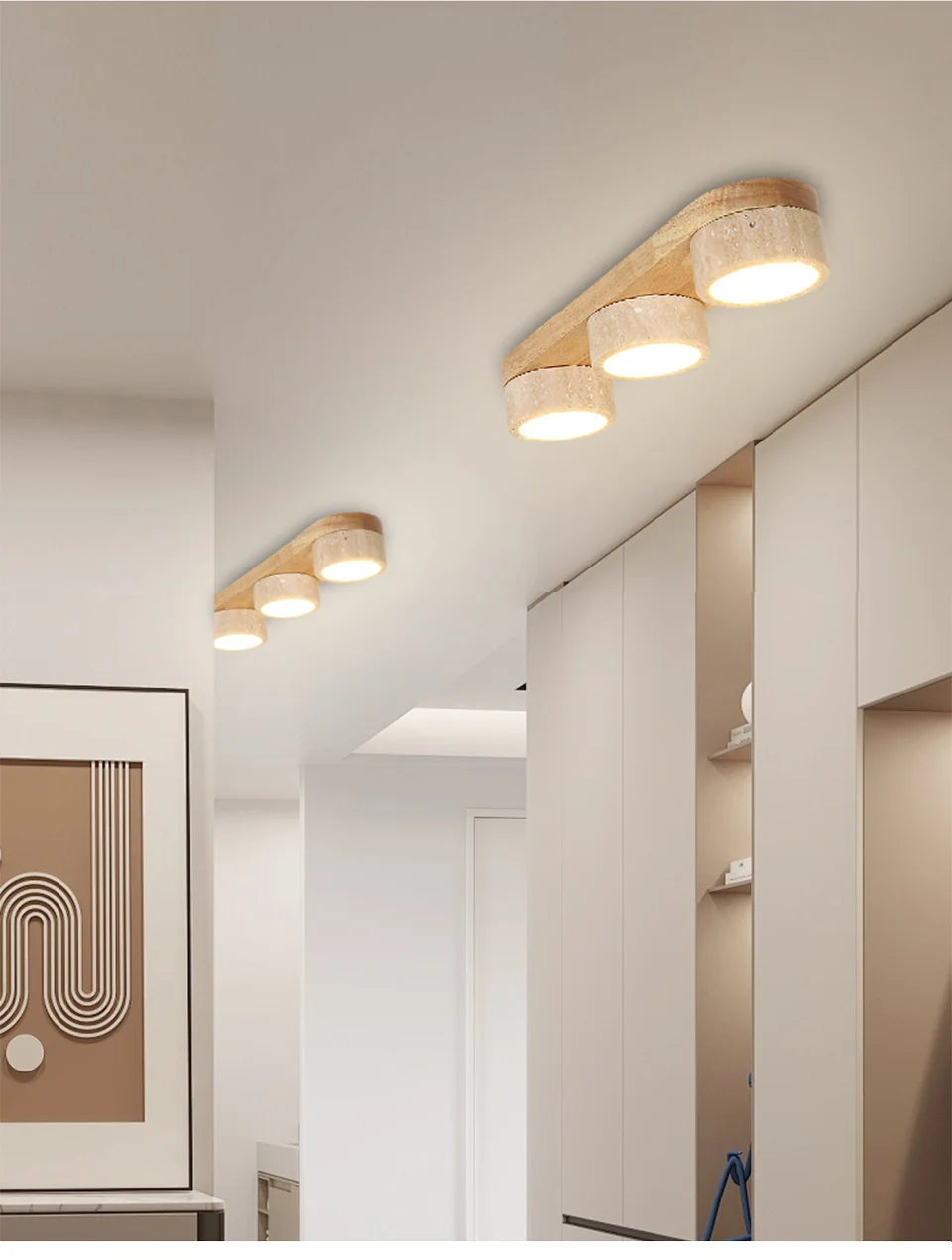 A bright hallway with multiple linear flush mount ceiling lights featuring natural stone and wood, mounted on a white ceiling.
