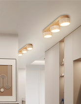 A bright hallway with multiple linear flush mount ceiling lights featuring natural stone and wood, mounted on a white ceiling.