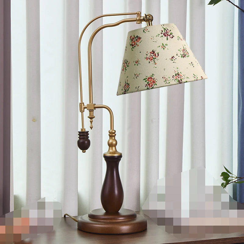 Decorative table lamp with floral lampshade on a wooden base in front of striped curtains.