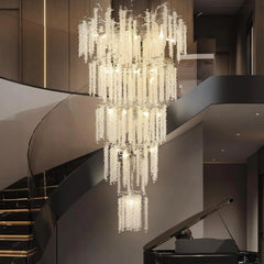 Luxurious chandelier hanging in a modern interior setting with a staircase and piano.
