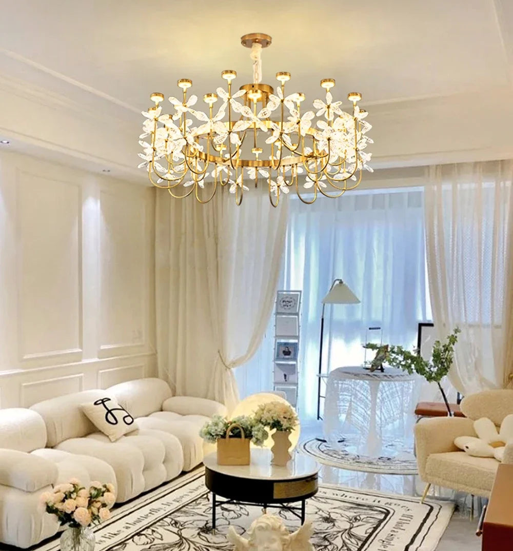 Modern living room with a gold chandelier, white sofa, and decorative elements.