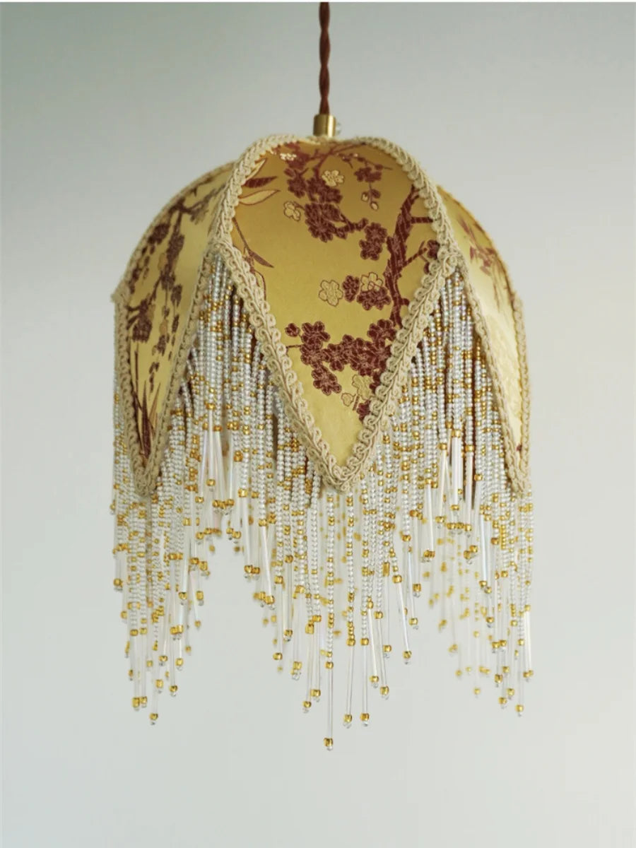 Decorative lamp with floral pattern and gold fringe on a plain background