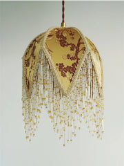 Decorative lamp with floral pattern and gold fringe on a plain background