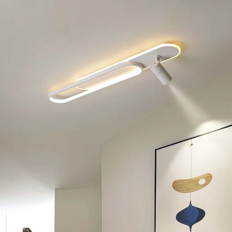 White linear ceiling lamp with an oval accent and one adjustable spotlight, casting a beam of light downwards.