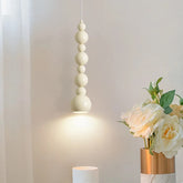 Cream gourd-shaped pendant light hanging over a table with a vase of flowers.