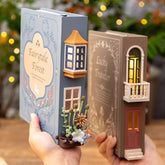 Two decorative bookend lamps, one designed as a blue book titled 'Fairytale Forest' with floral accents and illuminated windows, held in hands.