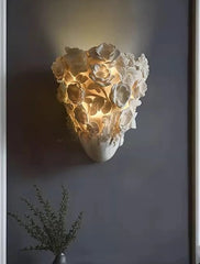 Decorative wall light fixture in a modern interior setting with a dark gray wall and a vase with greenery.