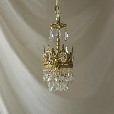 Small gold chandelier with crystal accents on a plain background
