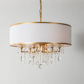 Gold drum shade chandelier with cascading clear crystals against a white background.