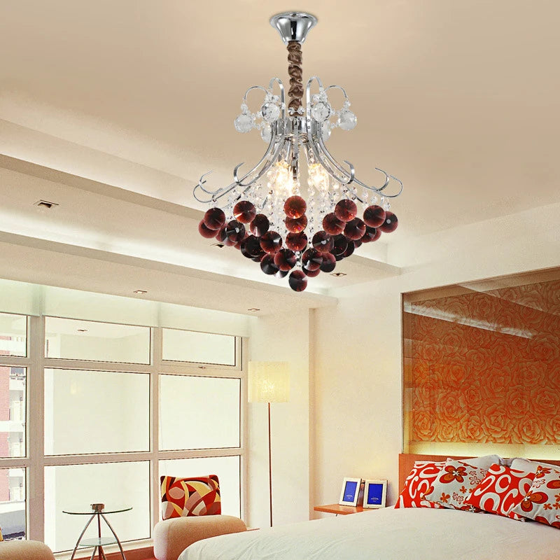 A crystal chandelier with wine red accents installed in a bedroom.