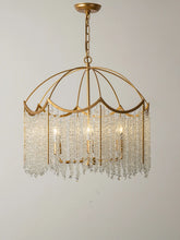 Close-up view of a gold-finished chandelier with cascading clear crystal droplets and internal lights against a plain background.