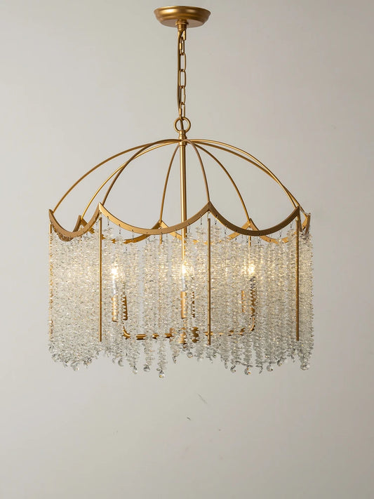 Close-up view of a gold-finished chandelier with cascading clear crystal droplets and internal lights against a plain background.