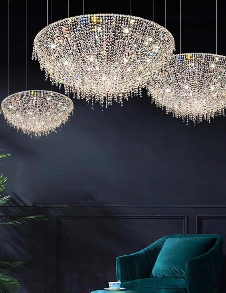Three crystal chandeliers hanging against a dark wall with a teal sofa in the foreground.