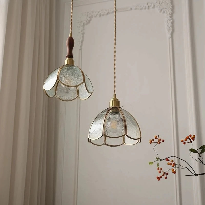 Two decorative pendant lights with glass shades hanging against a neutral wall.