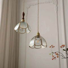 Two decorative pendant lights with glass shades hanging against a neutral wall.
