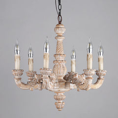 Slightly angled front view of a distressed wood candelabra chandelier showcasing its carved details and candle-shaped light sockets.
