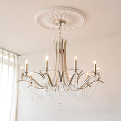 A spacious room featuring a brushed gold tiered crystal chandelier as the central light fixture.
