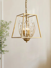 A gold metal cage pendant light with clear teardrop-shaped crystals hanging from curved wires, illuminated by three bulbs within.