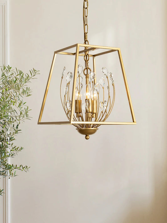 A gold metal cage pendant light with clear teardrop-shaped crystals hanging from curved wires, illuminated by three bulbs within.