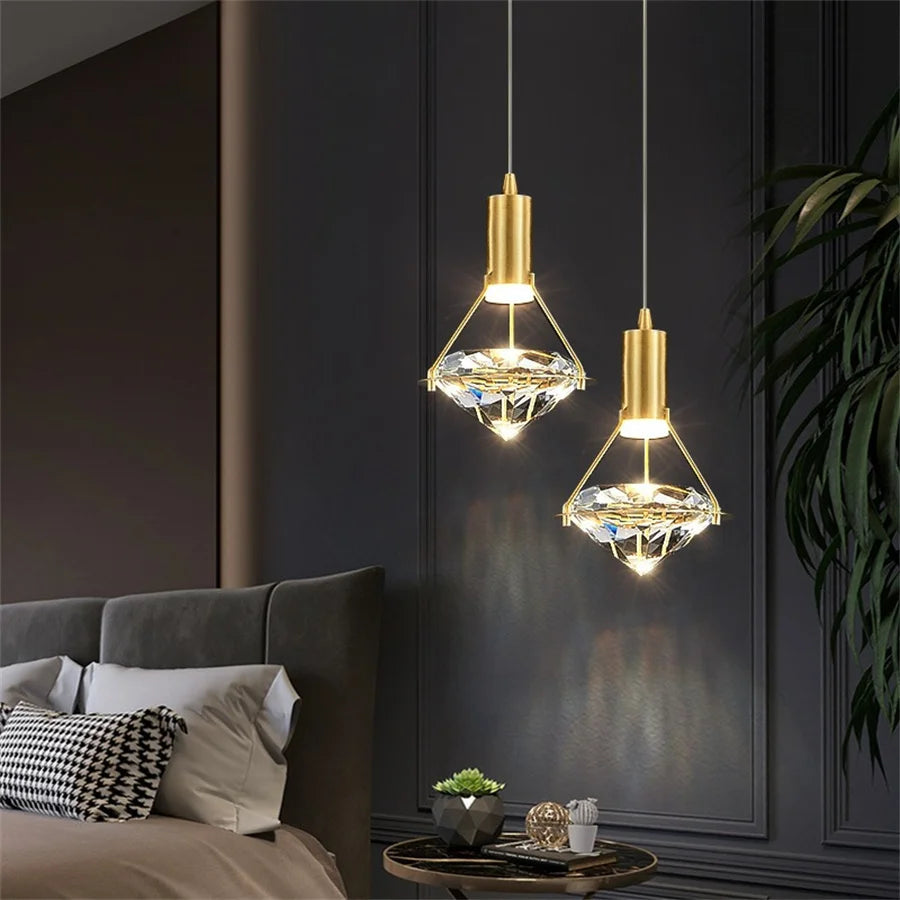 Two gold pendant lights hanging above a bed in a bedroom setting.