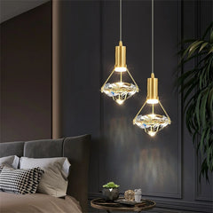 Two gold pendant lights hanging above a bed in a bedroom setting.