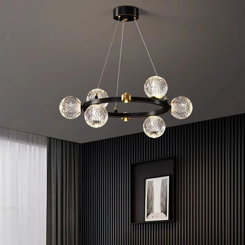 Modern chandelier with crystal balls hanging from a ceiling in a room with dark walls and a window.