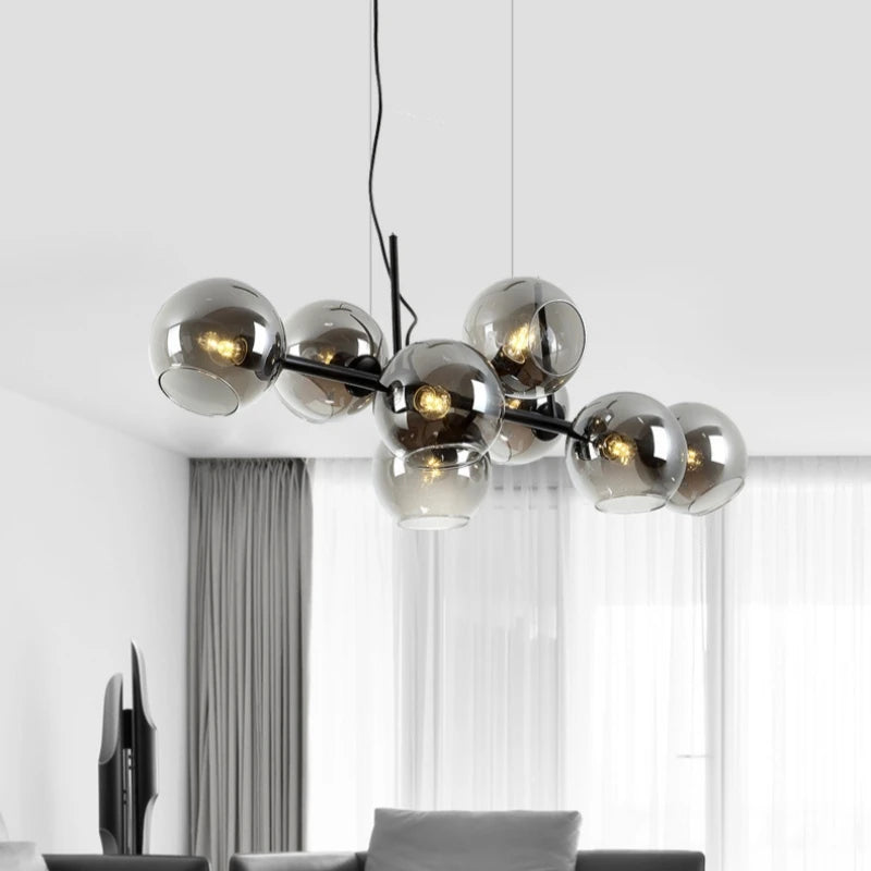 A modern chandelier with multiple smoked gray glass globes arranged on a black frame, suspended from a black cord.