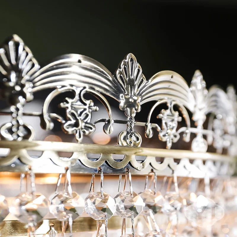 Close-up view of the polished chrome decorative metalwork and hanging faceted crystals on a tiered crystal chandelier.