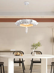 Modern dining room with a stylish chandelier, white table, and black chairs.