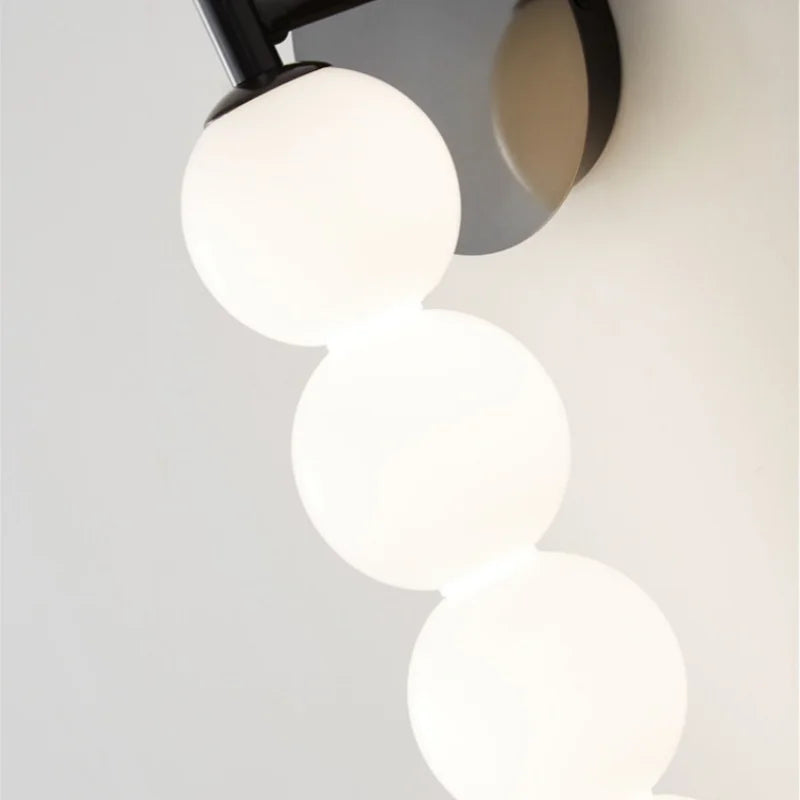 Close-up of a modern ceiling light fixture with three spherical white lights on a neutral background.