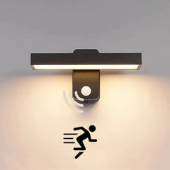 Black rotatable LED wall sconce mounted on a light gray wall, showing the motion sensor icon and a running figure.
