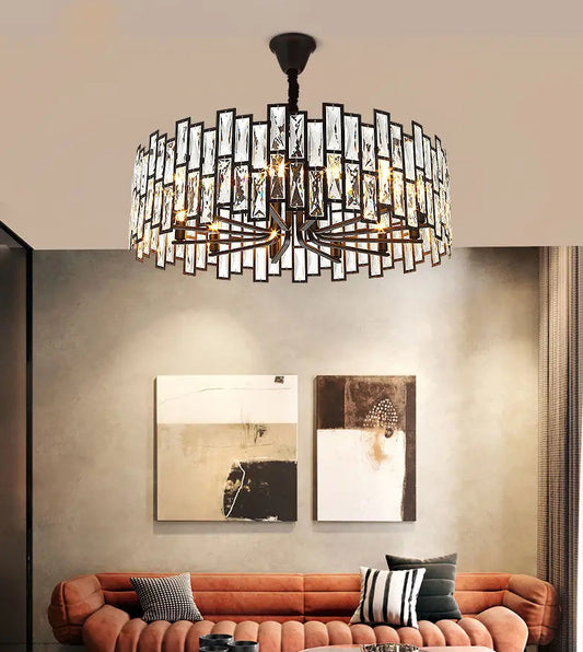 A circular chandelier with a black metal frame and clear crystal accents, suspended above a living room sofa.
