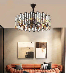A circular chandelier with a black metal frame and clear crystal accents, suspended above a living room sofa.