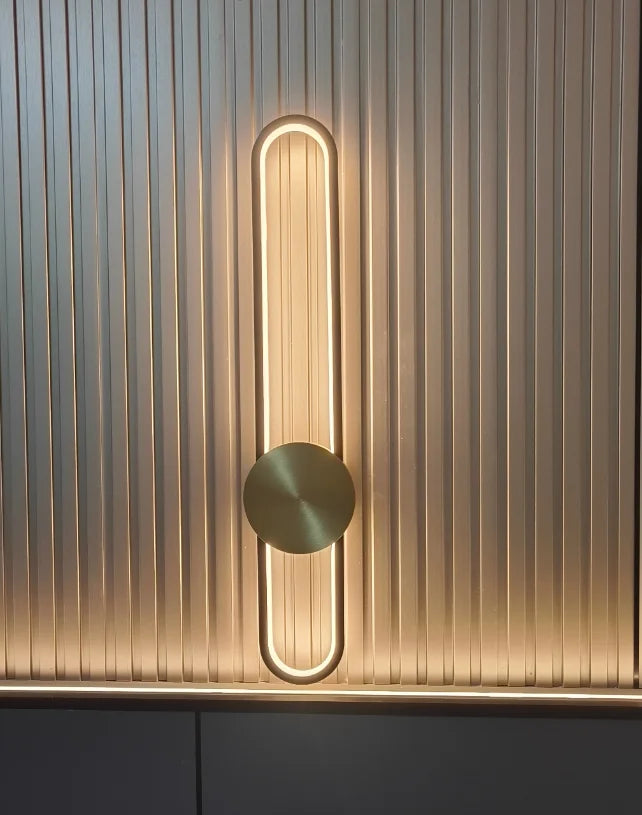 Modern wall light fixture with a circular design on a textured wall.