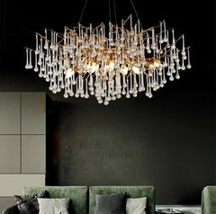 Luxury chandelier hanging above a green sofa in a modern living room setting.