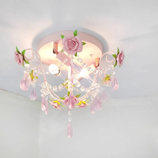 Close-up of a pink rose bouquet semi-flush ceiling light with crystal teardrop accents and a white painted metal frame.