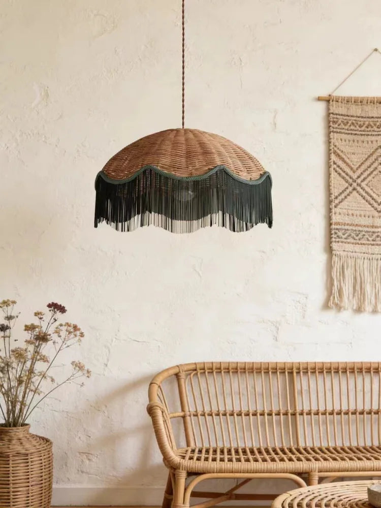 Woven rattan dome pendant light with a dark fringe hanging in a bohemian living room setting with rattan furniture