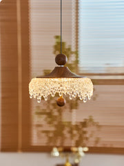 Decorative pendant light with wooden shade and crystal details in a room setting.