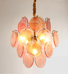 Chandelier with pink circular shades on a plain background