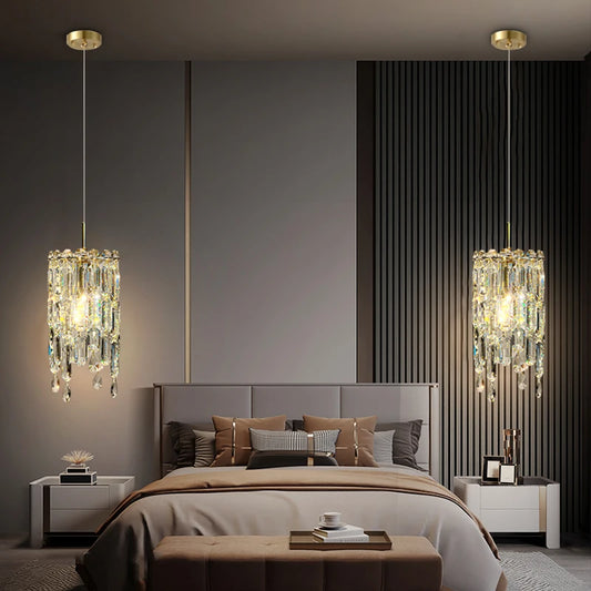 Gold tiered crystal pendant light hanging above a bed