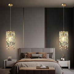 Gold tiered crystal pendant light hanging above a bed