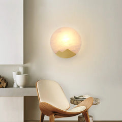 Modern interior with a wooden chair, round table, and wall-mounted light fixture.