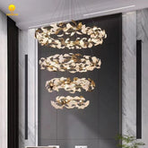 A multi-tiered chandelier with a gold frame shaped like rings adorned with white and gold leaf-like decorations, hanging in a modern interior.
