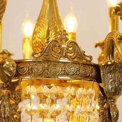 Detailed view of the gold chandelier's decorative finial and the top edge of the crystal-laden body.